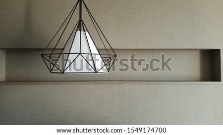 The geometric lamp in the bedroom has a gray wall background.