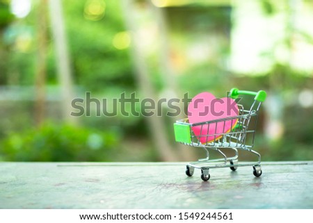 A photograph of a miniature shopping cart with a heart shape