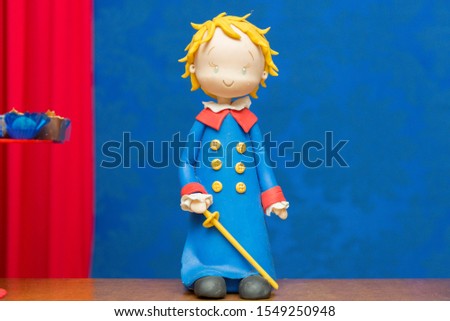 Kids birthday party decoration. Little prince theme party. Closeup of Little Prince in your small planet on blue arebesque background.