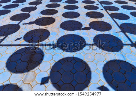 Shadow of hanging umbrellas on the blue brick floor ground  
