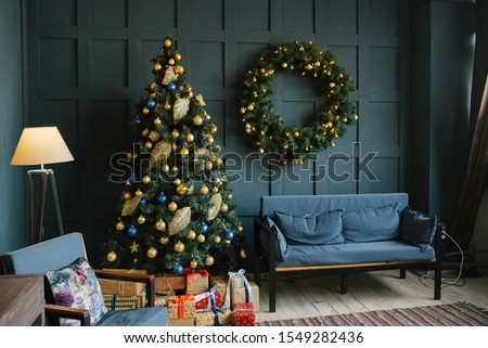Blue sofa with pillows and Christmas wreath on the wall in the living room in the loft style. Royalty-Free Stock Photo #1549282436