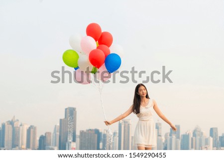 Follow your dream, Inspiration Concept - Young woman with colorful balloons having fun on rooftop balcony with cityscape at sunset. Fun, Vacation, Bright life
