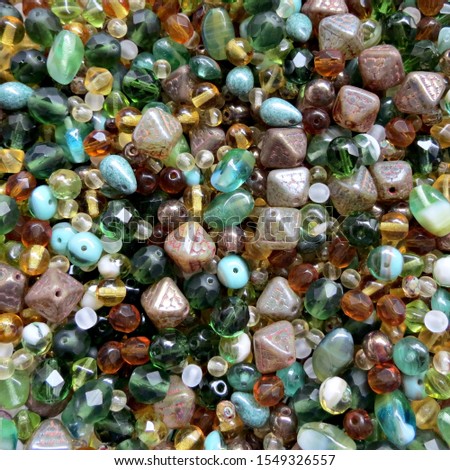 Green and brown glass beads mix for jewellery making. Hobby, handmade jewellery, fine arts. Beads texture. Close up. Royalty-Free Stock Photo #1549326557