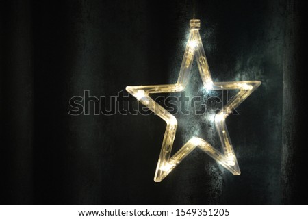 Close up of single electric lighted star with warm yellow lights against a dark backdrop decorations at home for Diwali, Christmas and New Year celebration