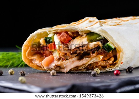 Tasty fast food: mexican burritos with guacamole sauce on black wooden background, selective focus