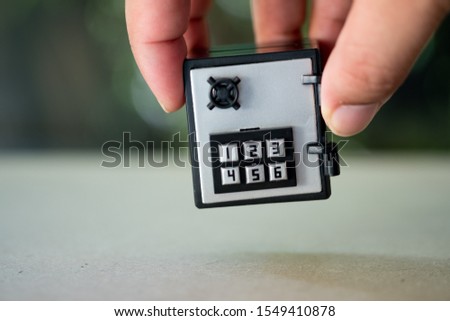 Man hand put miniature safe on wood table