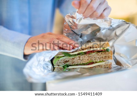 Close Up Of Woman Wrapping Sandwich In Non Reusable Aluminium Foil Royalty-Free Stock Photo #1549411409