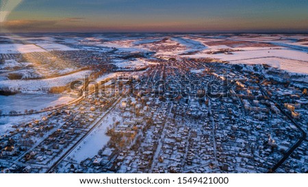 Top view of city suburbs or small town nice houses on winter sunset on cloudy sky background. Aerial drone photography concept.