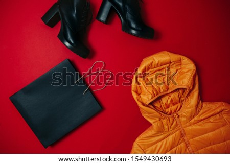 Black friday image with space for text. Bkack friday sale flat lay. Black friday bag, boots, wallet and bag on the red background.