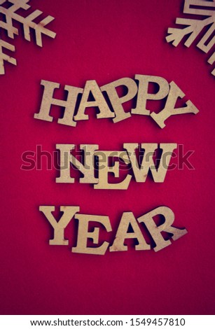 Happy New Year background.Red poster with hand made wooden letters in vintage rustic style.Winter holiday home decor.Wallpaper edited with film filter effect