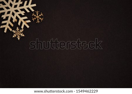 Winter holiday wallpaper.Hand made background with wooden rustic snow flakes.Dark brown backdrop for Happy New Year and Christmas Eve poster.Empty space for text and logo 