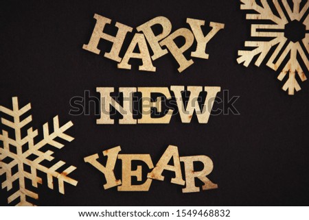 Happy New Year poster.Rustic wooden letters and snowflakes on dark brown background.Hand made wallpaper for winter holiday celebration.Vintage style and fading film filter