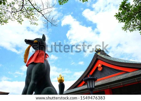 Statue of the fox-like deity Inari near the main hall of the Shinto shrine isolate on blue sky background in Kyoto, Japan.

