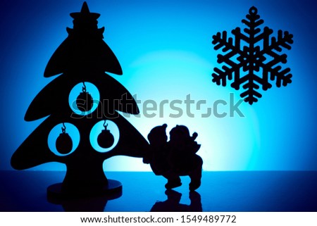 Silhouettes of Christmas tree, snowflakes and children on a blue background.