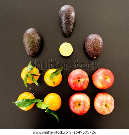 Arrangement of different healthy fruits and vegetables: apples, avocados, mandarine, lime, sweet potatoes. Shot on black background with light reflections. 
