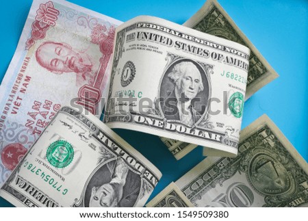 One-dollar bills and Vietnamese dongs on a blue background. American and Vietnamese currency.