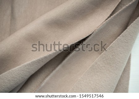 Soft towel fabric. Folds of cotton fabric. warm coat. Beautiful texture of beige and brown. A piece of fabric for a seamstress cut. The concept of warm cozy autumn.