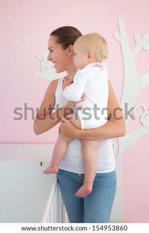 Profile portrait of a happy young woman holding cute baby and looking away