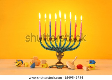 religion image of jewish holiday Hanukkah with menorah (traditional candelabra)and spinning top over yellow background