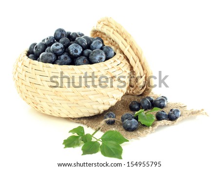 Blueberries in wooden basket on sackcloth isolated on white