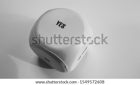 Anti stress big white foam dice with word "Yes" on white table in black and white