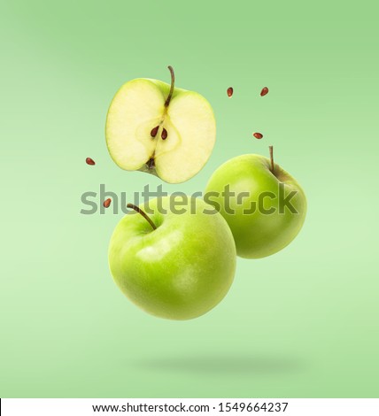 Flying fresh green apple with seeds on green background. Creative levitation food, summer fruits