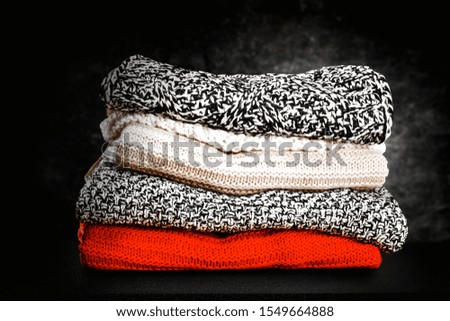 Dark mood photo of winter sweaters and free space for your decoration. Black board and dark wall of gray lights. Copy space. Chrsitmas time. Winter time. 