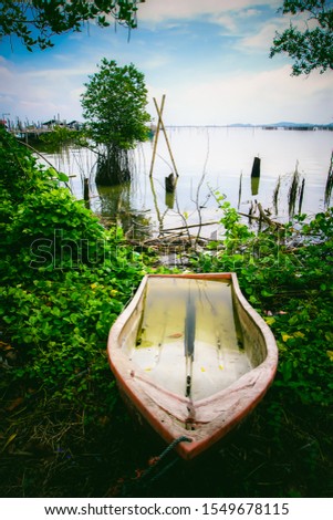 lLake view with boat. The wood boat on lake at sunset. Concept of loneliness, lacking direction, no leadership, rudderless, floating, listless or generally adrift without a goal. stillness calms Royalty-Free Stock Photo #1549678115