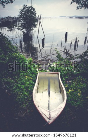 lLake view with boat. The wood boat on lake at sunset. Concept of loneliness, lacking direction, no leadership, rudderless, floating, listless or generally adrift without a goal. stillness calms Royalty-Free Stock Photo #1549678121