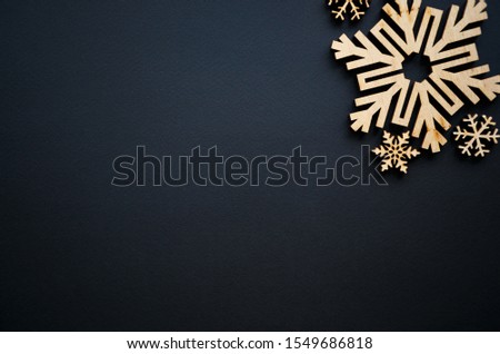 Christmas and New Year background.Hand made rustic wooden snow flakes on black backdrop for winter holidays wallpaper.Empty space for text on poster.Handmade crafts for holiday decor