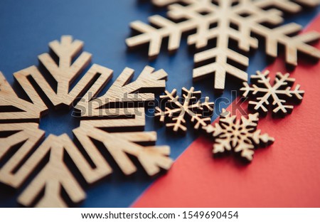 Hand made rustic snowflakes made from wood.Christmas and Happy New Year decor in close up.Blue and red color background for winter holidays.Wooden hand crafted objects for home decoration