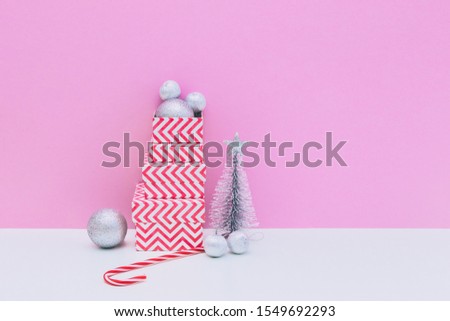 Silver fir tree, decoration balls, three sized gift boxes and candy cane on white and pink background. Christmas and new year concept. Winter holidays composition. Copy space, minimal art
