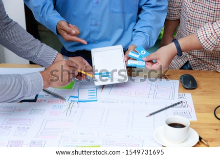 Graphic designers work together with UX UI designer planning application template layout framework for mobile phone computer mobile