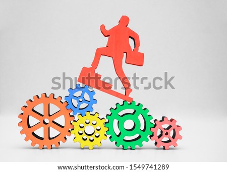 businessman with case running above many big and small gear wheel, cogwheel isolated on white background. wooden sign, symbol of business man. top manager. 