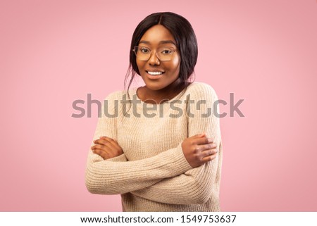 Shy Afro Girl Smiling At Camera Crossing Hands Standing Over Pink Background. Studio Shot