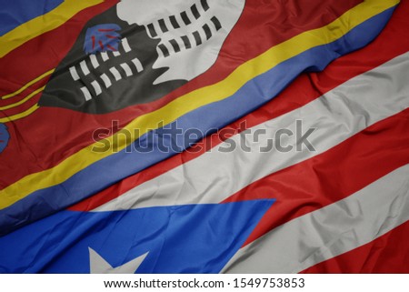 waving colorful flag of puerto rico and national flag of swaziland. macro