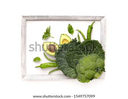 Creative picture for kitchen. Green vegetables inside frame on white background