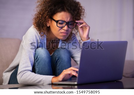 African-american student girl with bad eyesight using laptop, trying to make homework Royalty-Free Stock Photo #1549758095