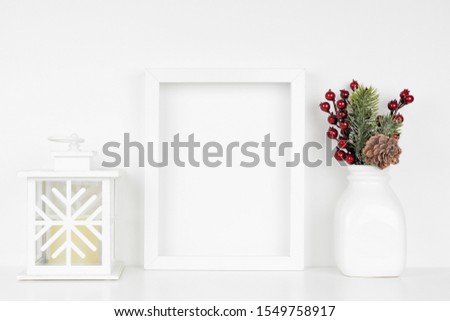Mock up white frame with Christmas lantern and decor on a shelf. Portrait frame against a white wall.