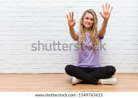 young blonde pretty woman smiling and looking friendly, showing number eight or eighth with hand forward, counting down