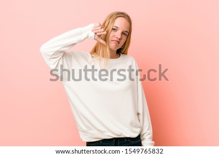 Young blonde teenager woman showing a dislike gesture, thumbs down. Disagreement concept.