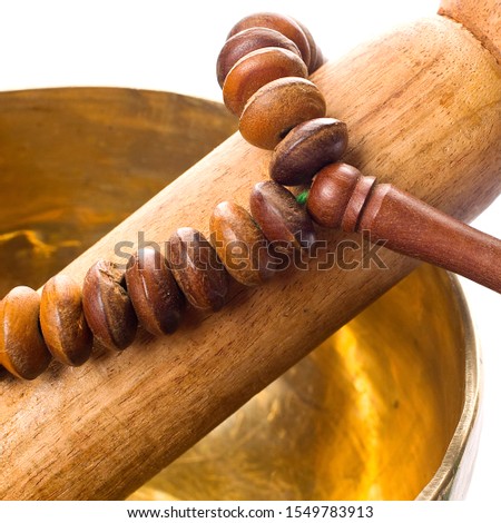 Details of a singing bowl with its mallet and a japamala on a wooden table