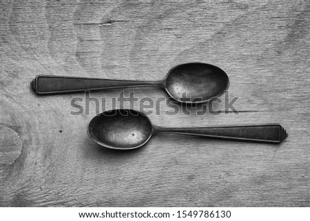 Black and white photography.
Old vintage metal  spoons on a wooden background.
