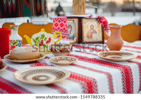Delicious Christmas kutia in a clay pot, standing on a festive table, next to bread, compote, fruit. Christian Traditions Celebrating Christmas