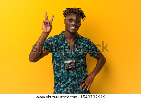 Young black rasta man wearing a vacation look joyful and carefree showing a peace symbol with fingers.
