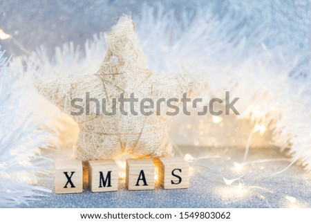 Christmas star on a light blue glittered background with wooden cubes forming word Christmas 