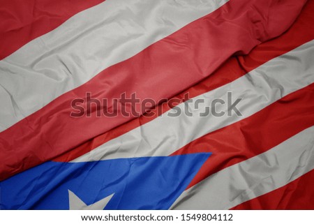 waving colorful flag of puerto rico and national flag of austria. macro