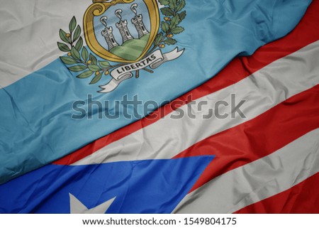 waving colorful flag of puerto rico and national flag of san marino. macro