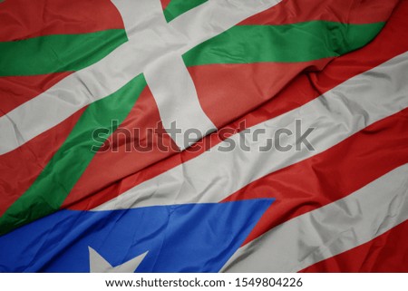 waving colorful flag of puerto rico and national flag of basque country. macro