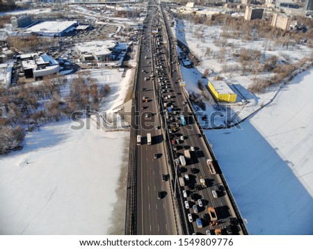 Panoramic aerial view on the Leningradsky Highway on a cold sunny day in winter. Beautiful urban landscape river covered with ice. Cars on the bridge.Drone shot.